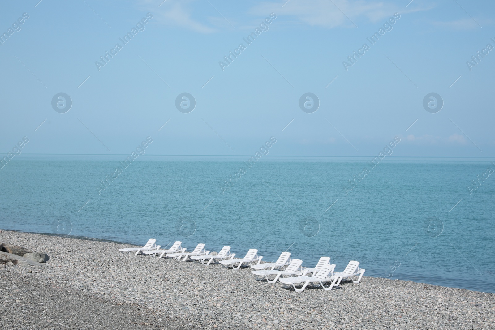 Photo of Beautiful view of sunbeds on pebble beach near sea