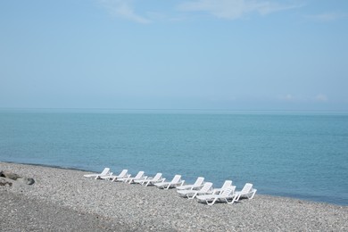 Photo of Beautiful view of sunbeds on pebble beach near sea