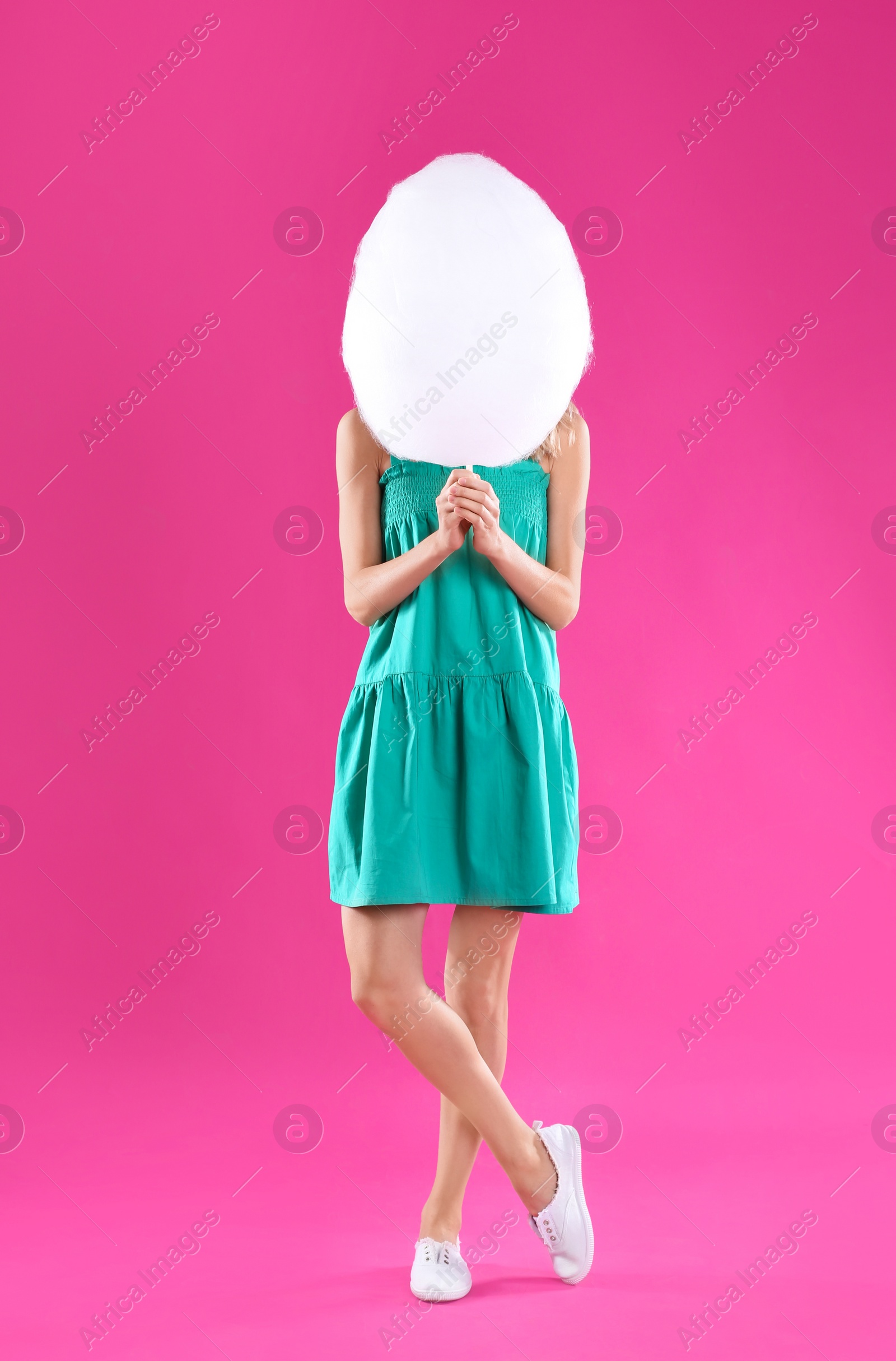 Photo of Young woman with cotton candy on pink background