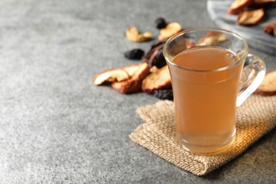 Delicious compote in glass cup and dried fruits on grey table. Space for text