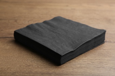 Photo of Stack of black clean paper tissues on wooden table
