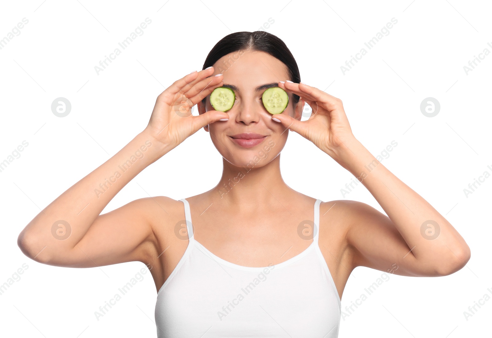 Photo of Beautiful young woman putting slices of cucumber on eyes against white background