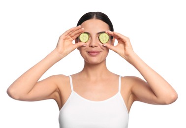 Photo of Beautiful young woman putting slices of cucumber on eyes against white background