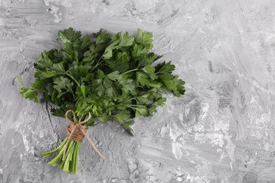 Photo of Bunch of fresh green parsley leaves on grey textured table, top view. Space for text