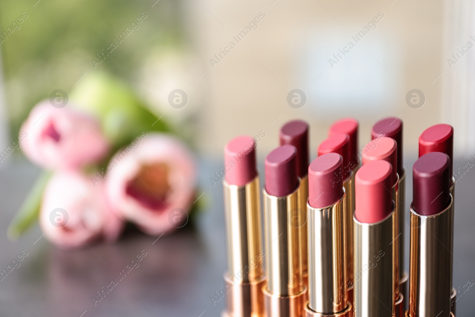 Photo of Set of bright lipsticks on blurred background. Space for text