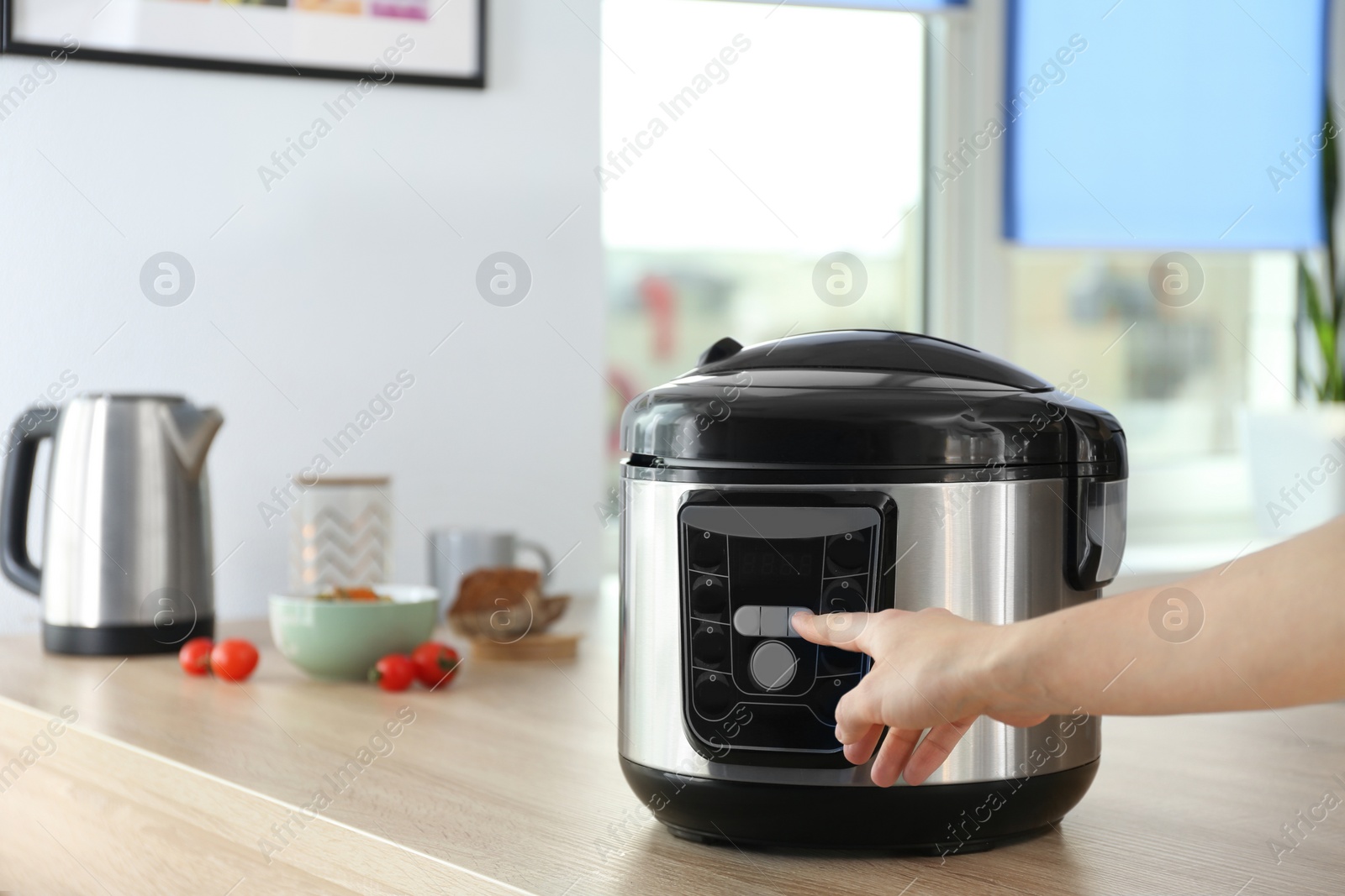 Photo of Woman turning on modern electric multi cooker in kitchen. Space for text