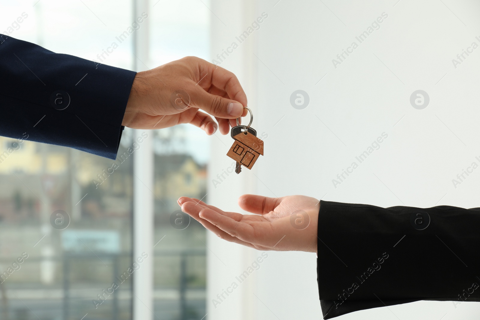 Photo of Real estate agent giving key to client in new house, closeup