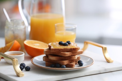 Photo of Toasted bread with jam and fresh blueberries on tray in kitchen