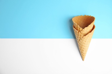 Empty wafer ice cream cones on color background, flat lay. Space for text