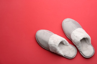 Pair of soft slippers on red background, flat lay. Space for text