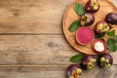 Photo of Purple mangosteen powder and fruits on wooden table, flat lay. Space for text