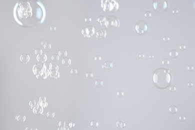 Beautiful transparent soap bubbles on light grey background