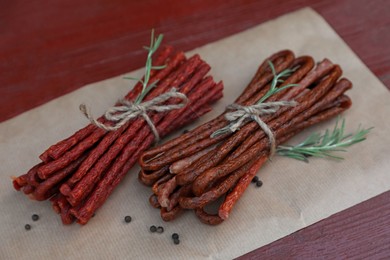 Photo of Tasty dry cured sausages (kabanosy) and spices on wooden table