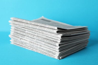 Photo of Stack of newspapers on light blue background. Journalist's work