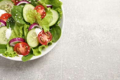 Delicious salad in bowl on light grey table, top view. Space for text
