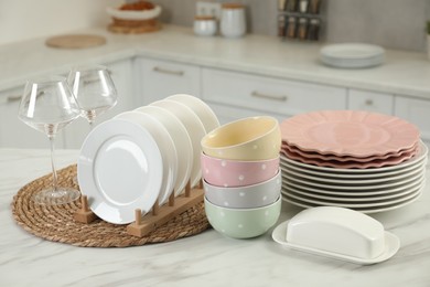 Photo of Clean plates, bowls, butter dish and glasses on white marble table in kitchen