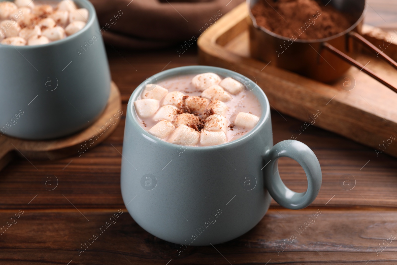 Photo of Cups of aromatic hot chocolate with marshmallows and cocoa powder on wooden table, closeup