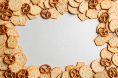 Photo of Frame of delicious crackers on light table, flat lay. Space for text