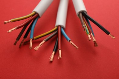 Photo of Electric cables with wires on red background, closeup view
