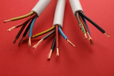 Electric cables with wires on red background, closeup view