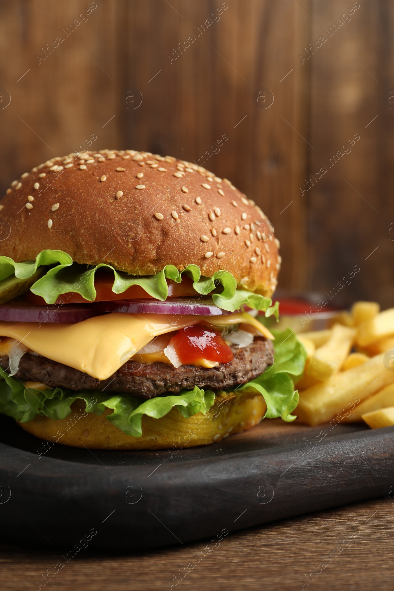 Photo of Delicious burger with beef patty and french fries on wooden table, closeup