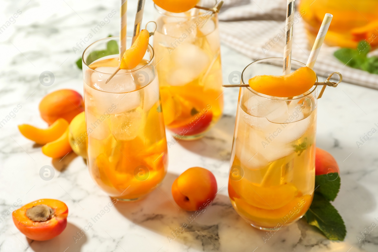 Photo of Delicious refreshing drink with apricot on white marble table