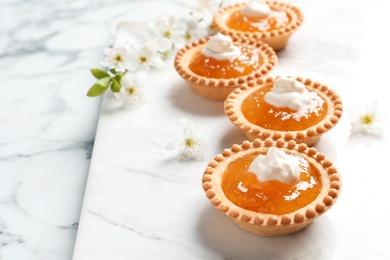 Photo of Tasty tartlets with jam on light background, closeup