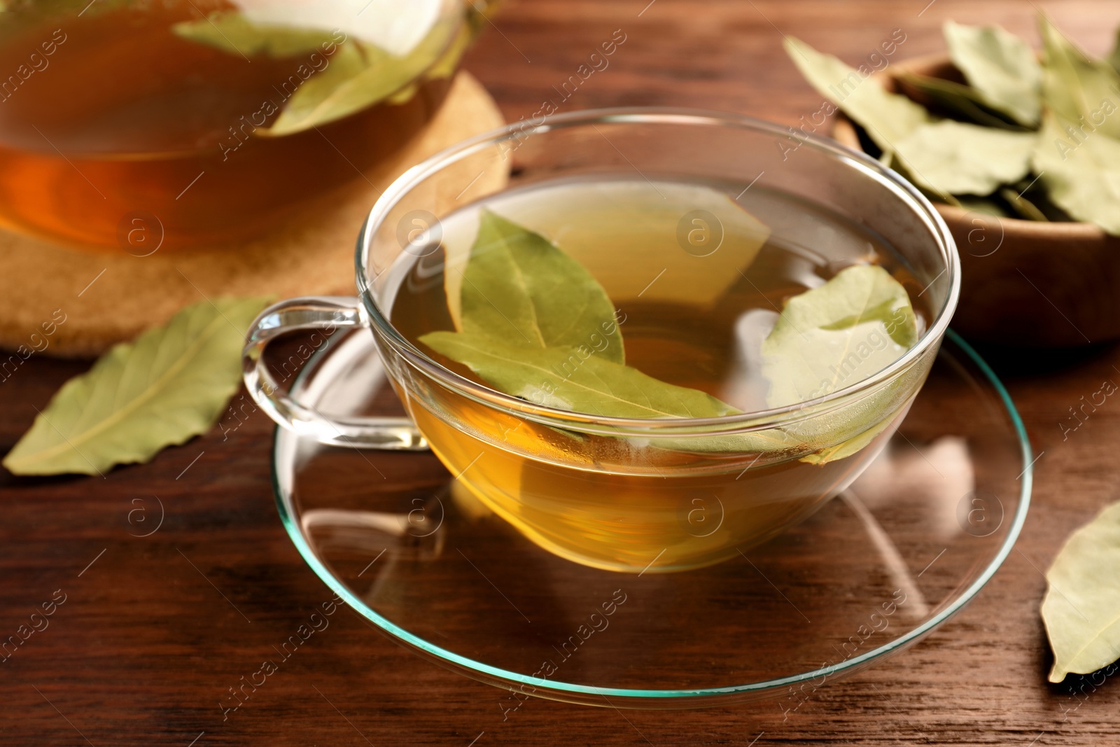 Photo of Cup of freshly brewed tea with bay leaves on wooden table, closeup