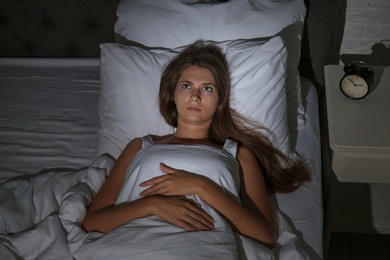 Photo of Young woman suffering from insomnia in bed at home