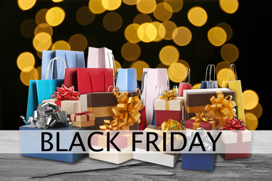 Image of Black Friday. Many gift boxes and shopping bags against black background with blurred lights