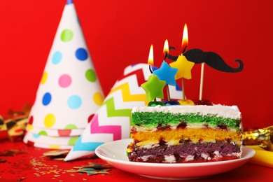 Piece of birthday cake with candles on red background, space for text