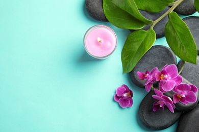 Flat lay composition with orchid and spa stones on turquoise background. Space for text