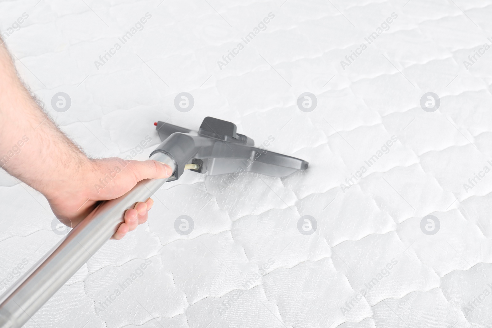 Photo of Man disinfecting mattress with vacuum cleaner, closeup. Space for text