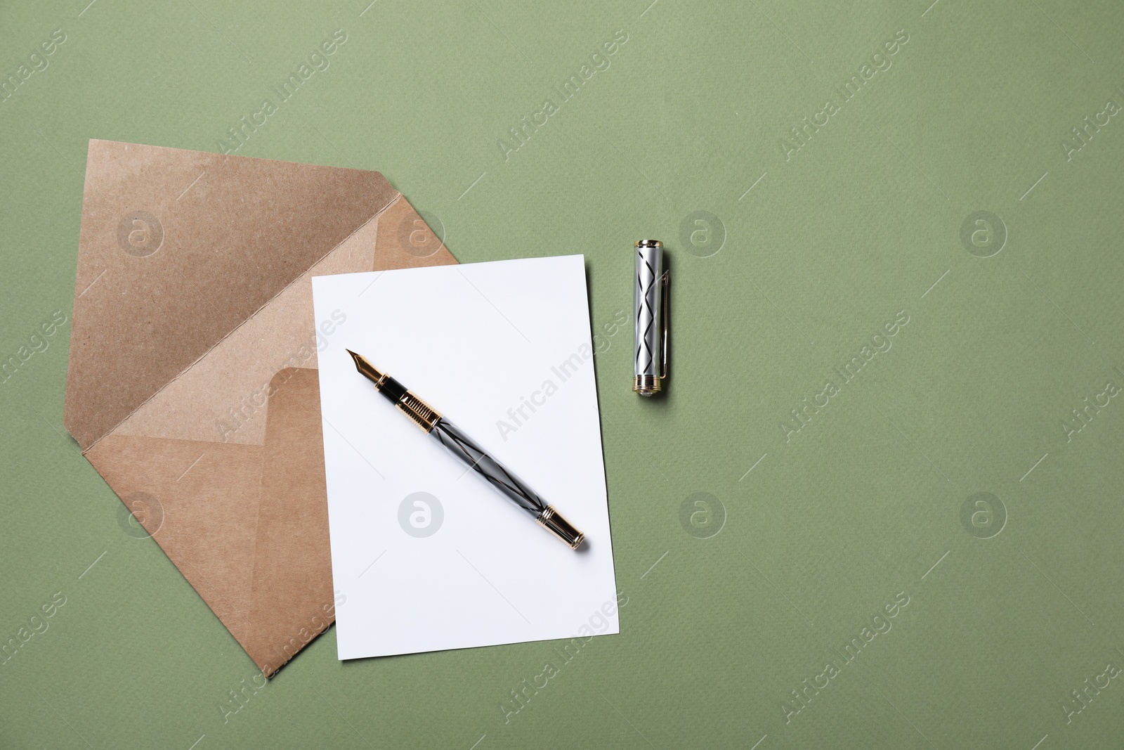 Photo of Blank sheet of paper, letter envelope and pen on green background, top view. Space for text