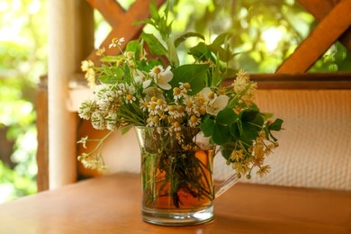 Photo of Composition with different fresh herbs in cup of tea on wooden table indoors