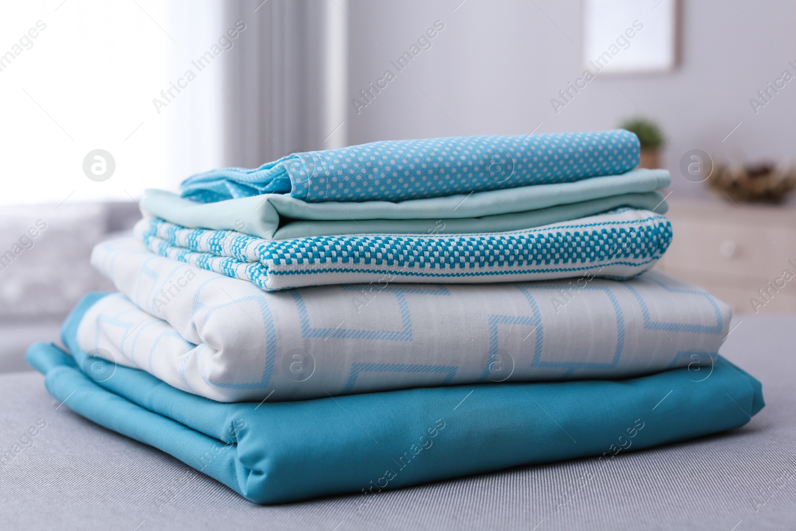 Photo of Stack of clean bed linens on table in room