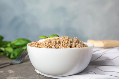 Photo of Tasty buckwheat porridge with butter on grey table