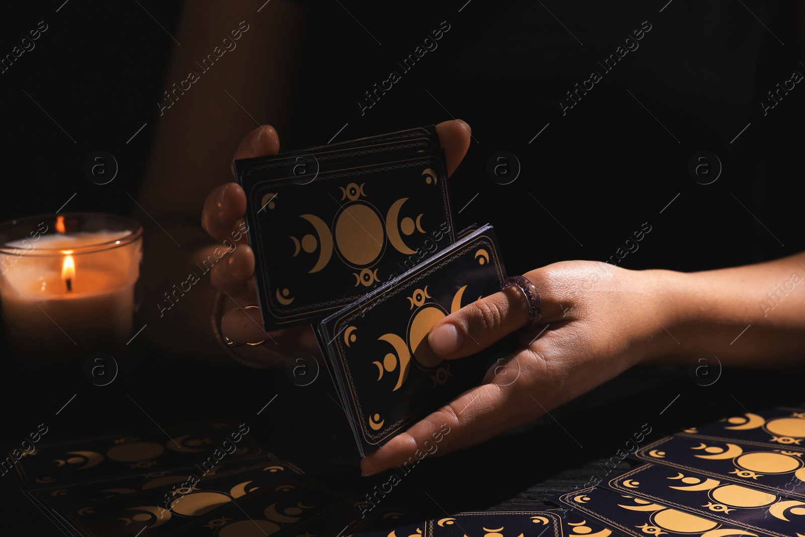 Photo of Soothsayer shuffling tarot cards at table in darkness. Fortune telling