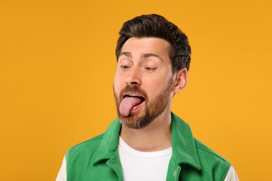 Photo of Man showing his tongue on orange background