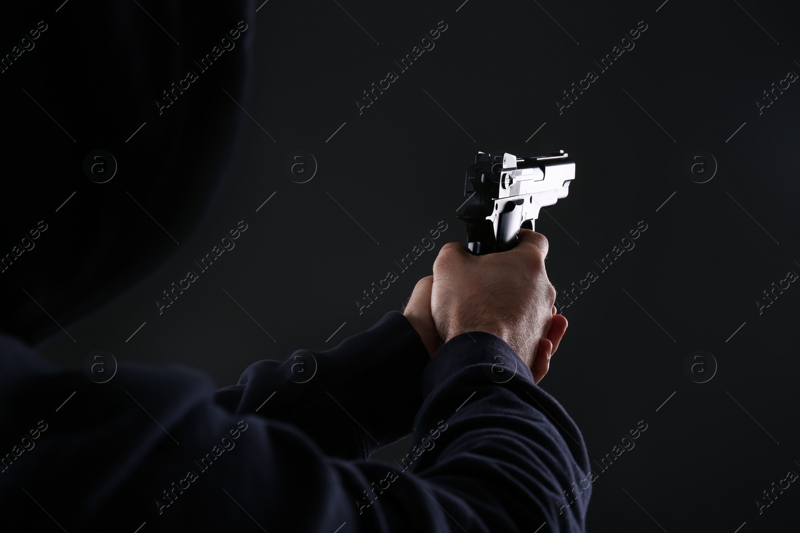 Photo of Man holding gun on black background, closeup