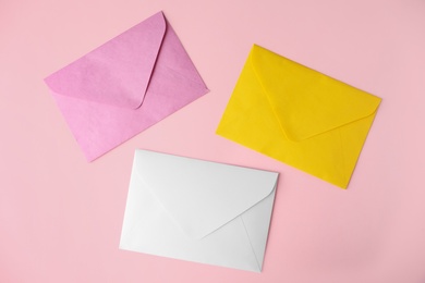 Photo of Colorful paper envelopes on pink background, flat lay