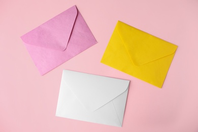 Colorful paper envelopes on pink background, flat lay