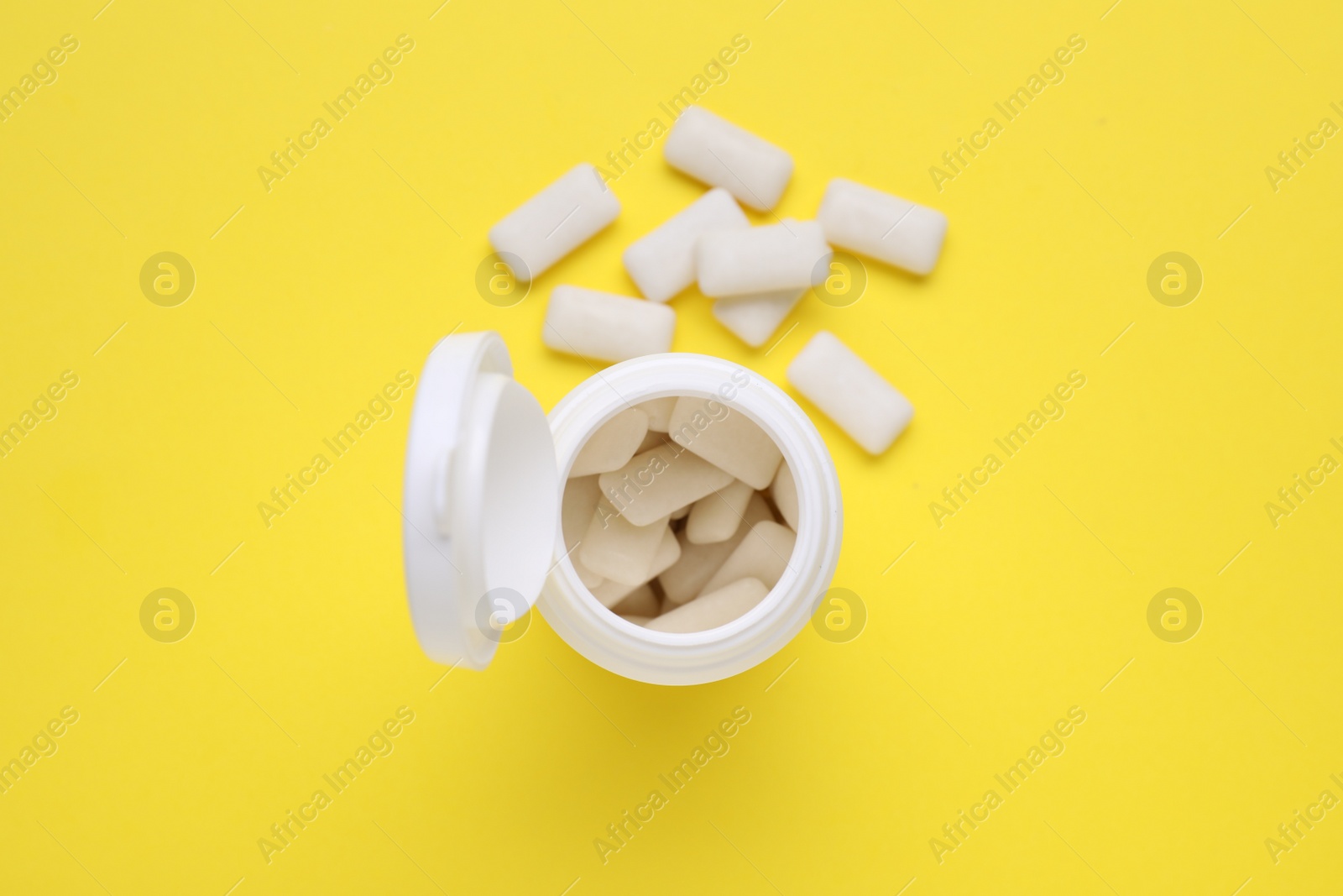 Photo of Jar with chewing gums on yellow background, flat lay