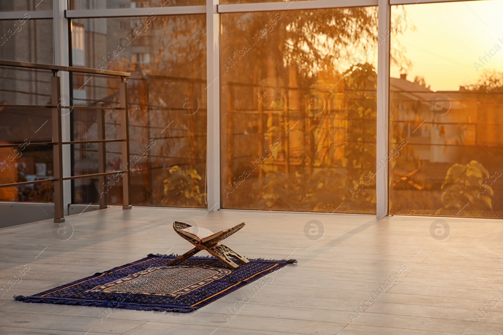 Photo of Rehal with open Quran on Muslim prayer rug indoors. Space for text