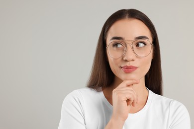 Photo of Curious woman wearing glasses on light gray background, space for text