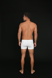 Photo of Man in underwear on black background, back view
