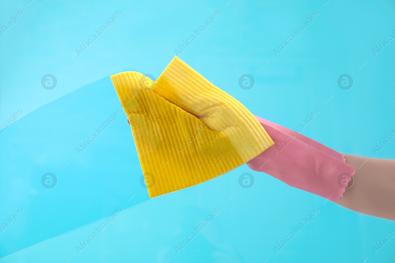 Image of Young woman wiping glass with rag against color background. Cleaning service 