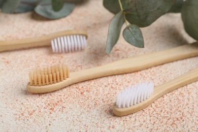 Photo of Bamboo toothbrushes on beige textured table, closeup