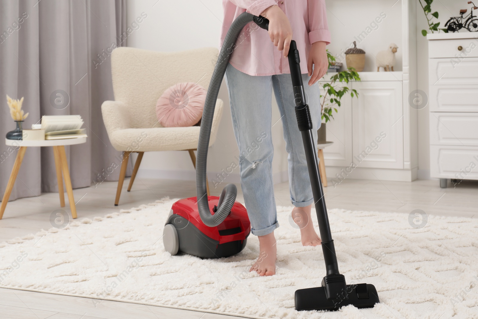 Photo of Woman cleaning carpet with vacuum cleaner at home, closeup