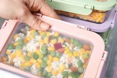 Woman taking box with vegetable mix from refrigerator, closeup